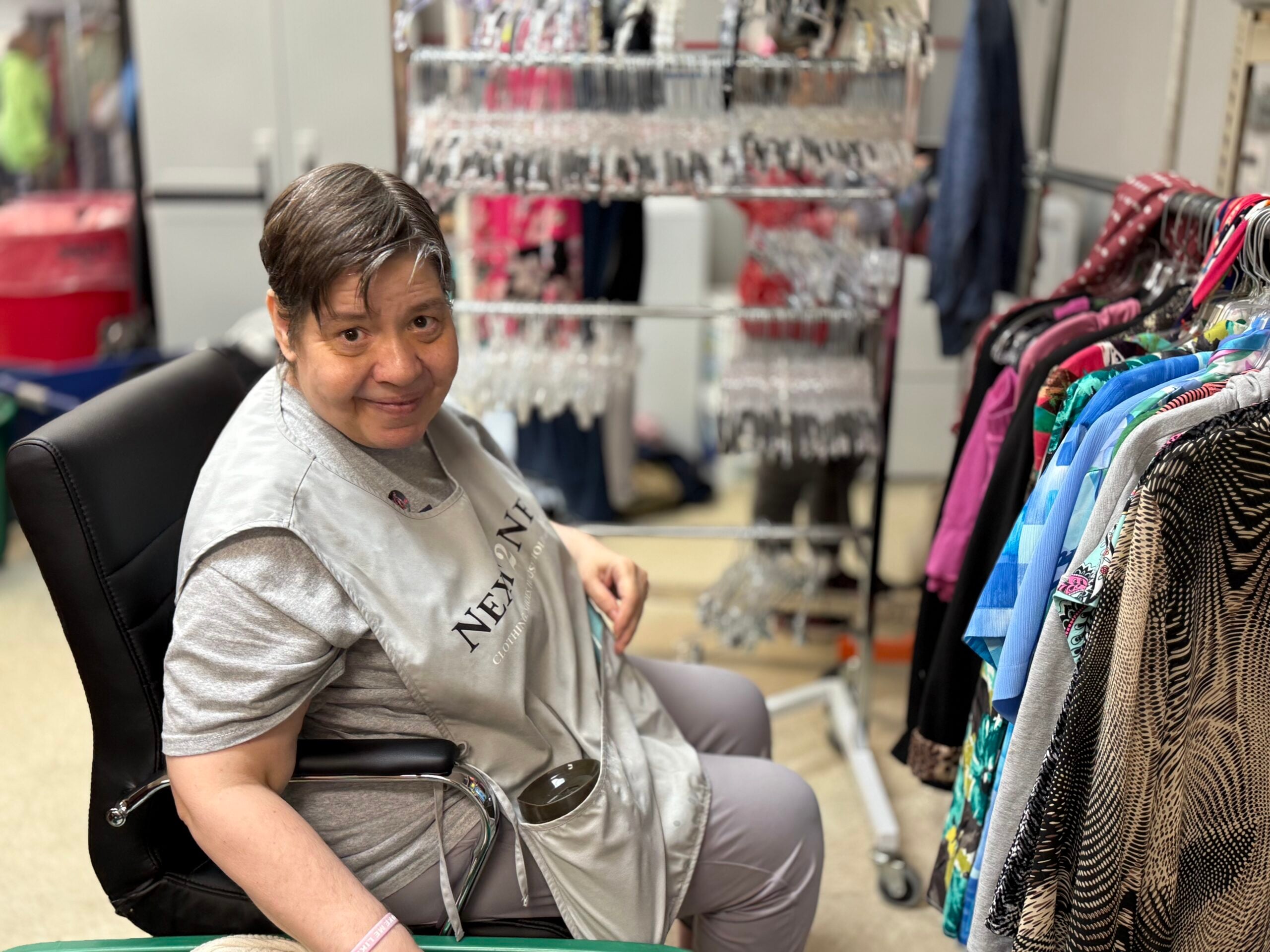 person sitting in a chair at a clothing store smiling for photo