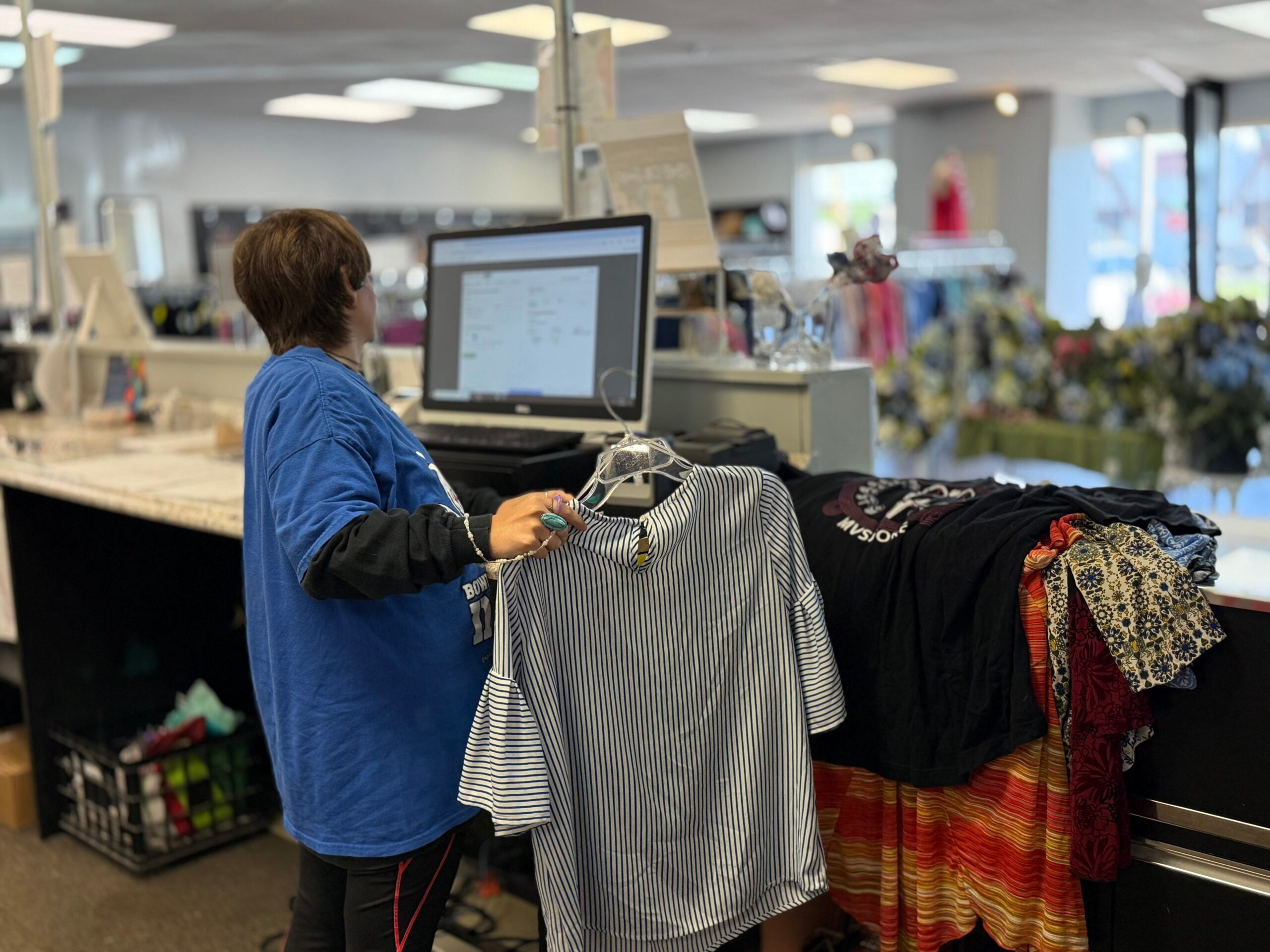 woman holding clothes looking at computer